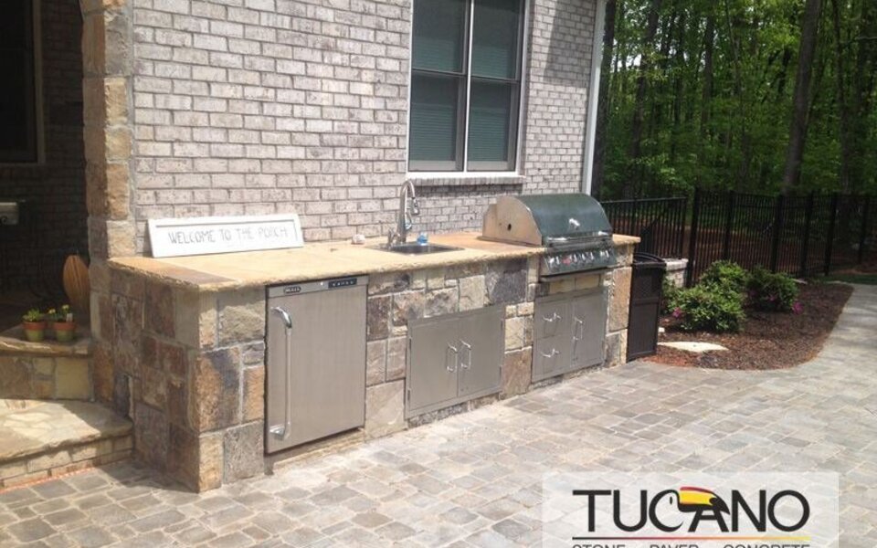 Custom outdoor kitchen with stone veneer and built-in grill on paver patio in Metro Atlanta